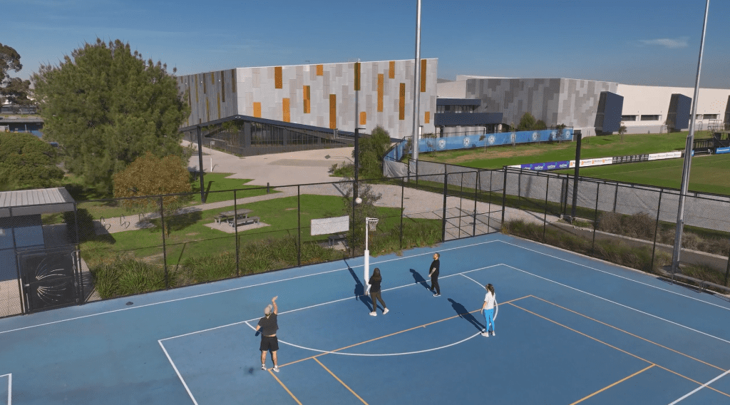 Exterior shot of Narrandjeri Stadium, with people playing on outdoor courts